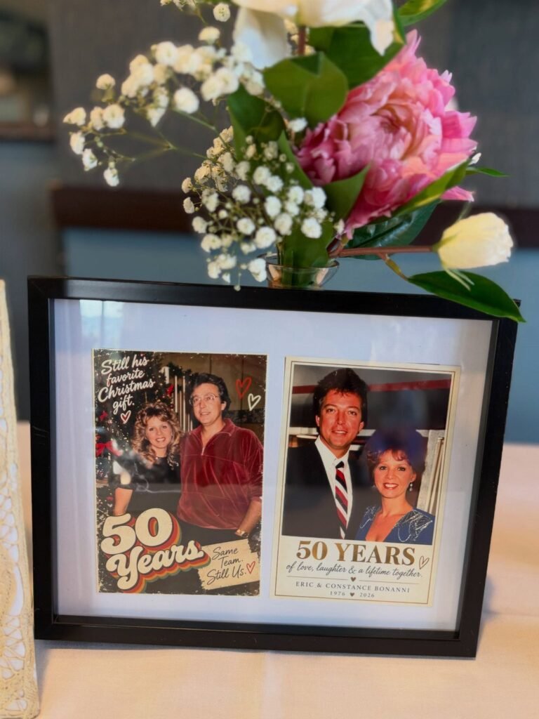 Framed photos of a couple celebrating 50 years married next to fresh flowers.