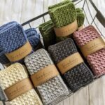 Folded textured cotton washcloths in various colors inside a metal wire basket.