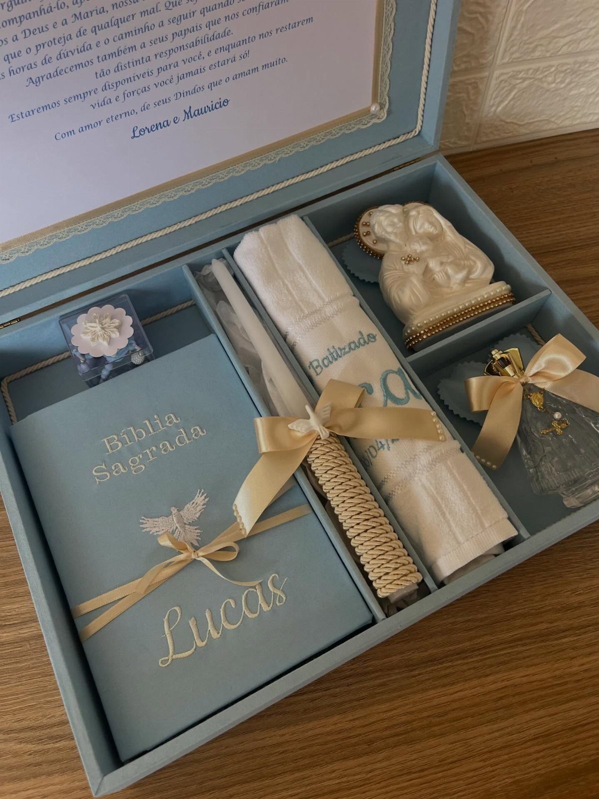 Blue christening gift set with personalized Bible, candle, and religious figurines in a box.
