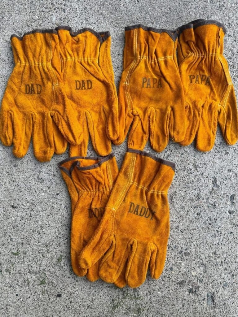 Tan leather work gloves with Dad, Papa, and Daddy printed on them.