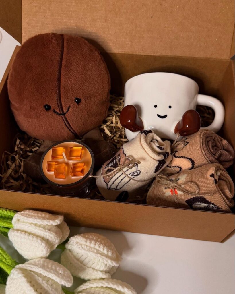 Coffee themed gift box with bean plushie, smiling mug, candle, and socks.