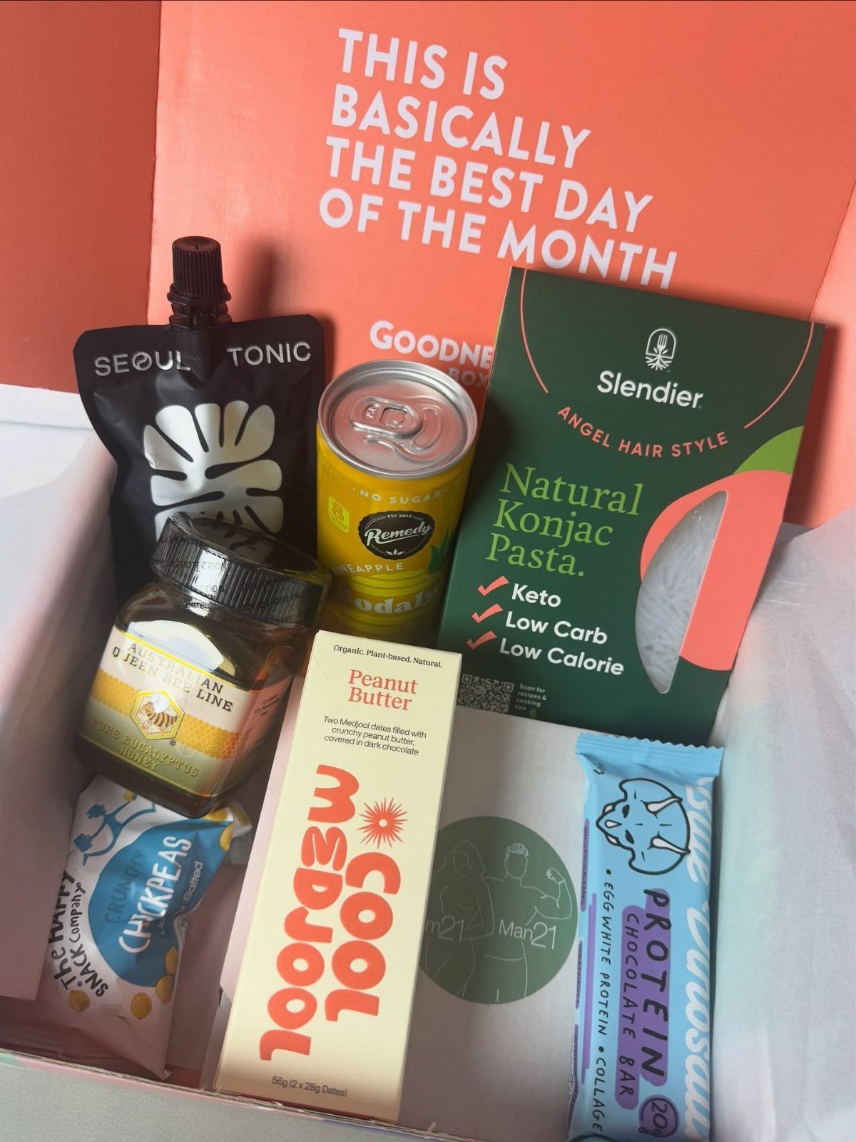 Assorted gourmet snacks and drinks arranged inside a white gift subscription box.