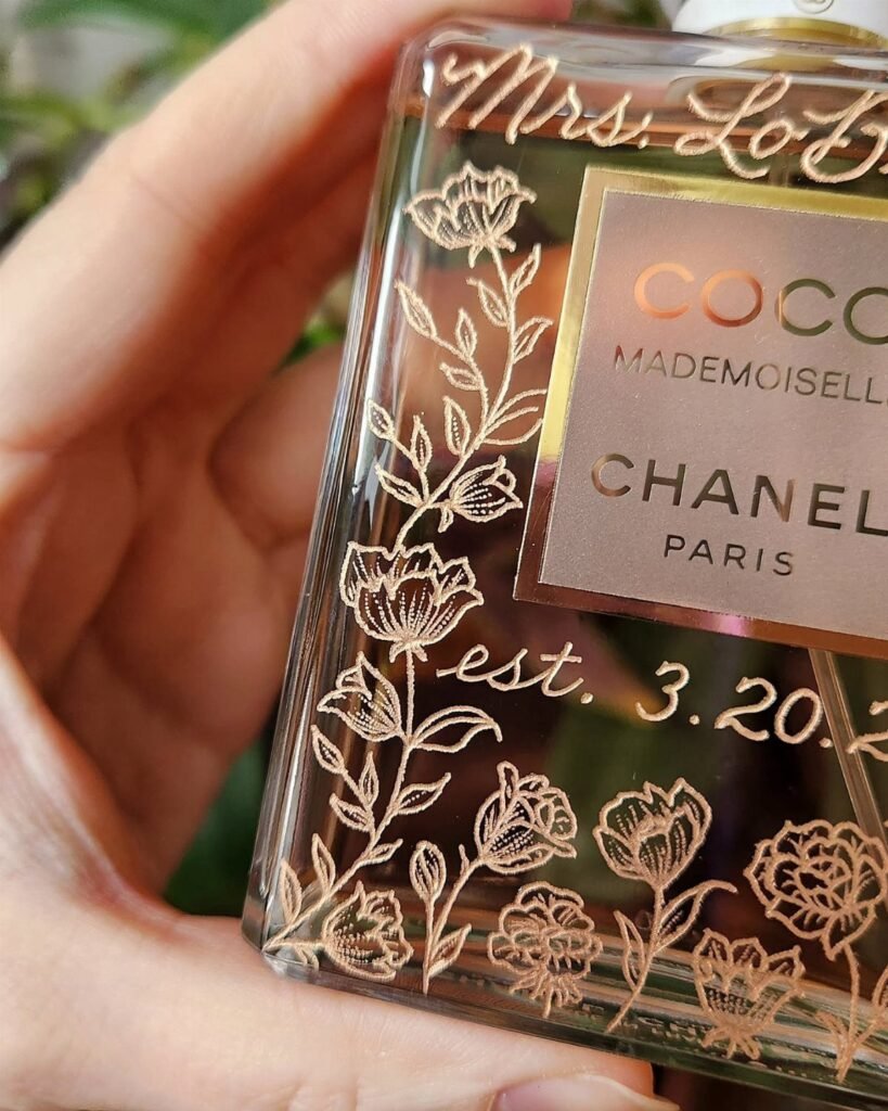 Engraved Chanel perfume bottle with gold floral designs and personalized text held by hand