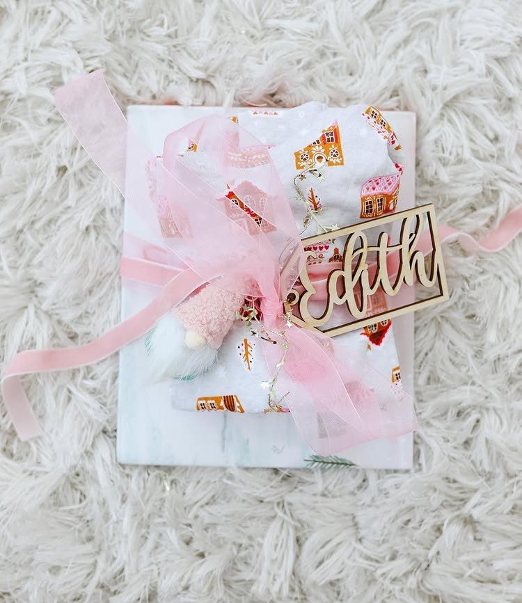 Wrapped gift with pink ribbon and wooden name tag on white shaggy rug