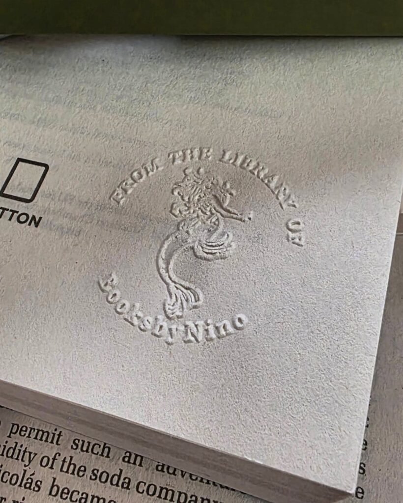 Embossed library seal on a white book page with a mythical creature design.