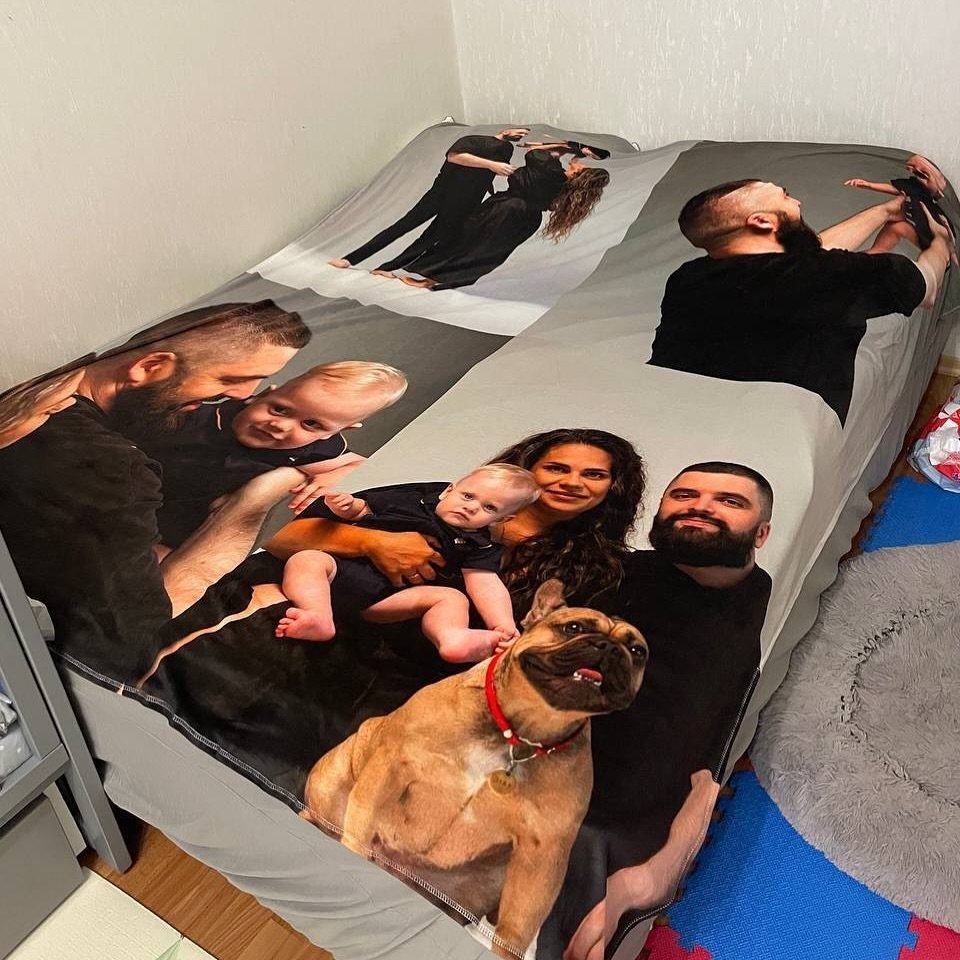 Custom photo blanket on a bed featuring a family and their bulldog.