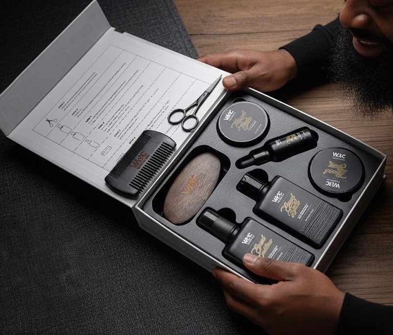 Beard grooming kit in a black box with scissors, comb, and care products.