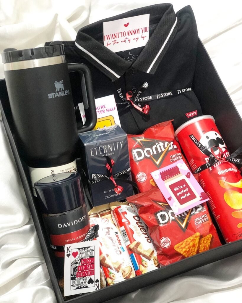Gift box for men containing a polo shirt, tumbler, cologne, and various snacks.
