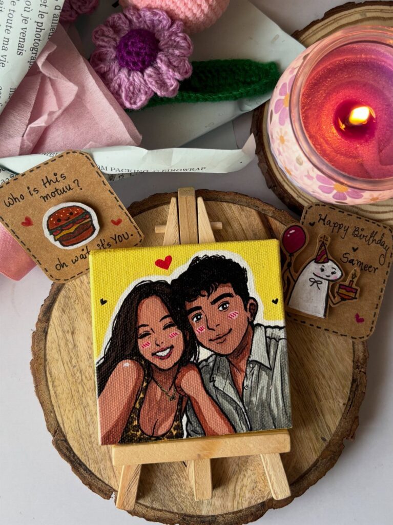 Small canvas painting of a couple on an easel surrounded by birthday gifts.