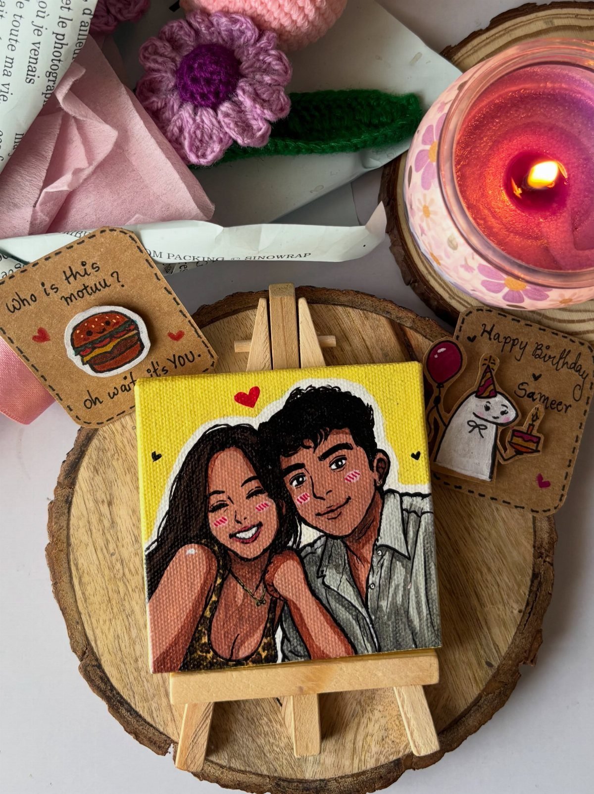 Small canvas painting of a couple on an easel surrounded by birthday gifts.