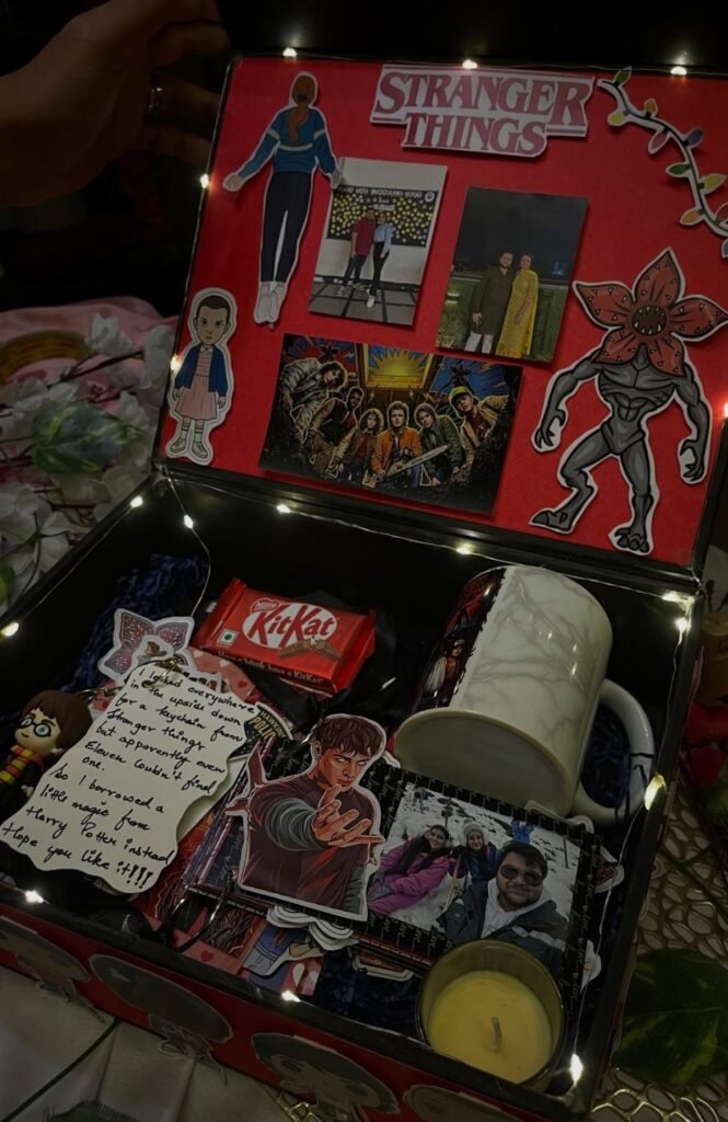 Stranger Things themed gift box with character cutouts, photos, a mug, and candy.