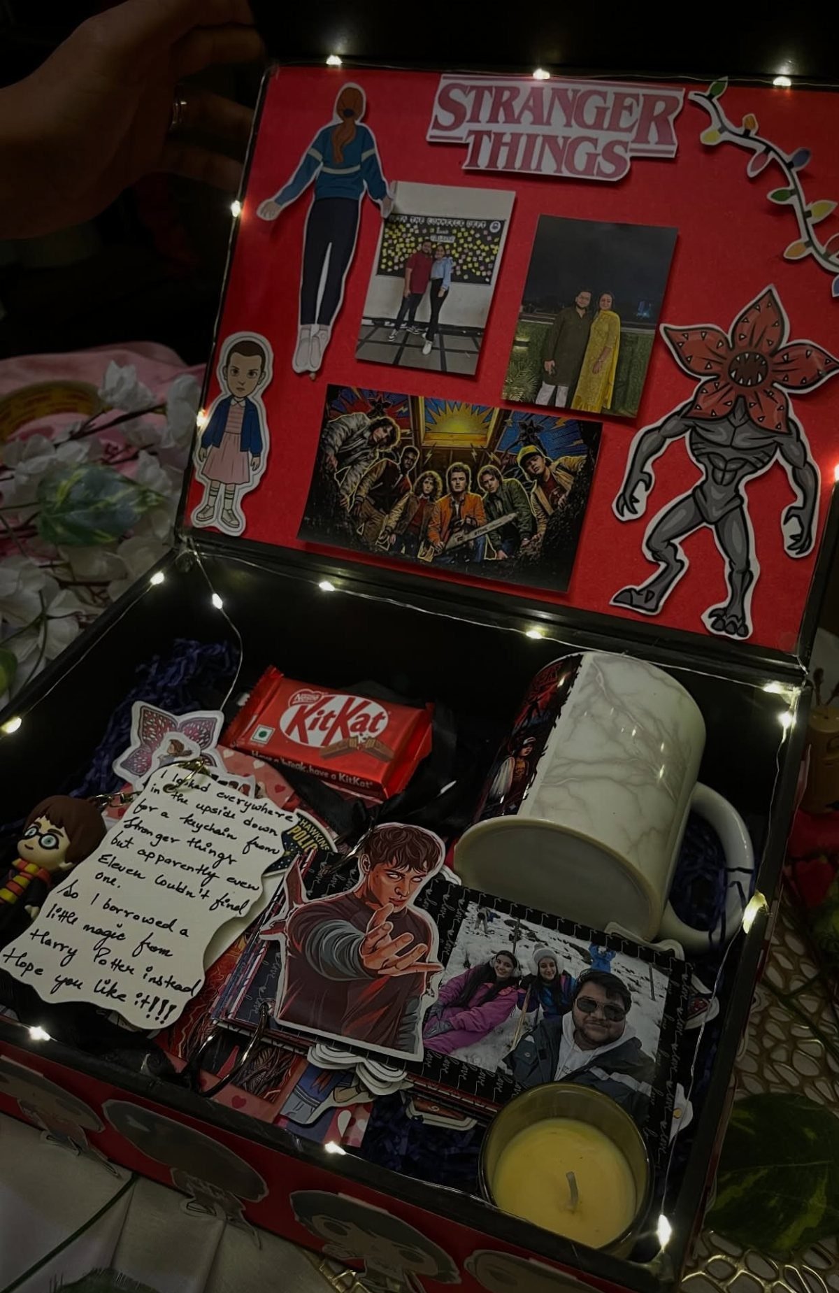 Stranger Things themed gift box with character cutouts, photos, a mug, and candy.