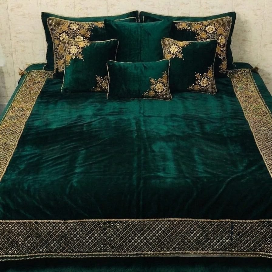 Emerald green velvet bedding with ornate gold embroidery on a bed.
