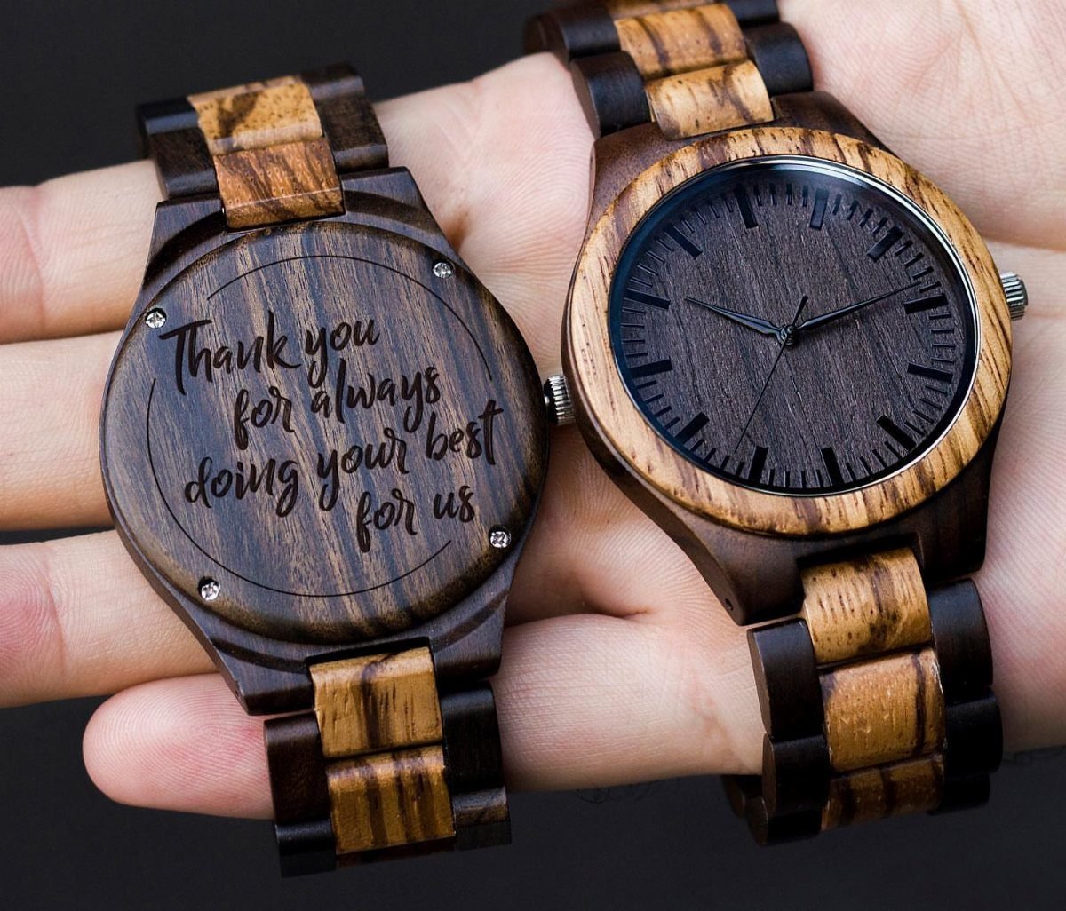 Two wooden wristwatches, one showing the face and one showing an engraved back.