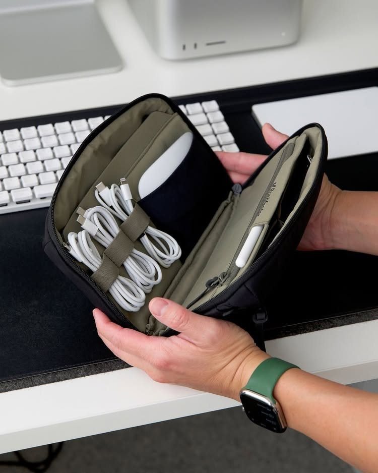 Black tech pouch held open showing organized white cables and electronic accessories.